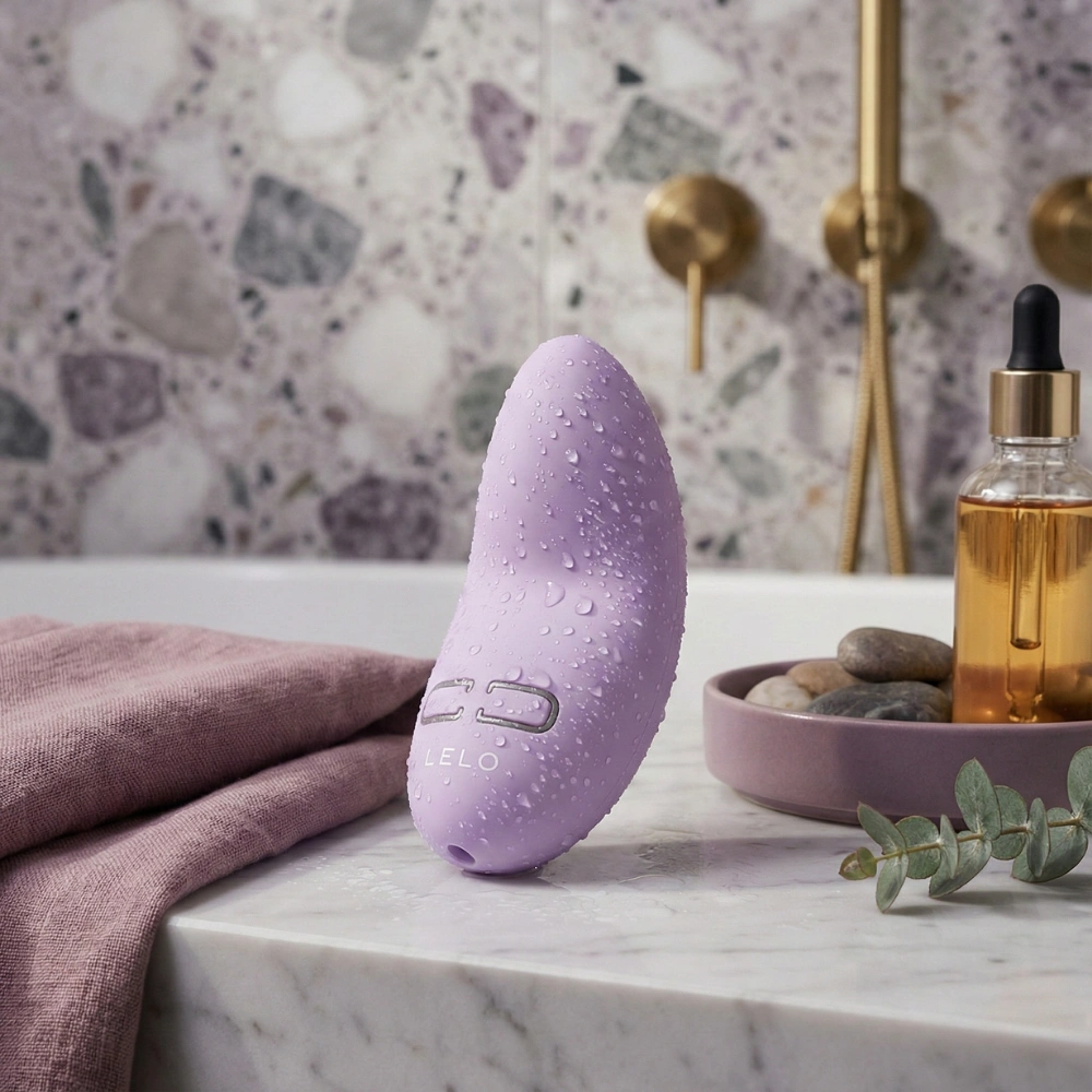Vibromasseur étanche Lelo Lily 3 lilas avec gouttes d'eau sur marbre blanc.
