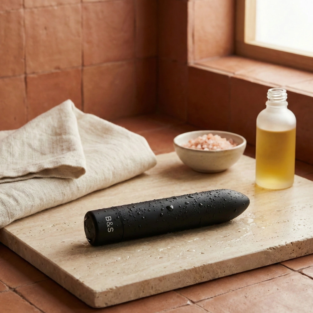 Sextoy de voyage compact Kernex 2 posé sur une pierre naturelle avec serviette.